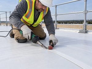 Roofing inspector checking flashing and seams after a commercial roof replacement