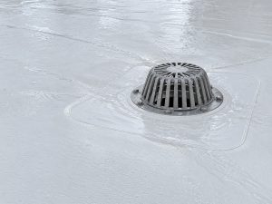 Clear roof drain on a white TPO commercial roof in New Albany, IN, with sloped insulation guiding rainwater
